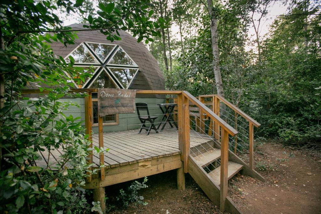 una terraza de madera con una mesa y una silla. en Bosque Vivo en Recinto