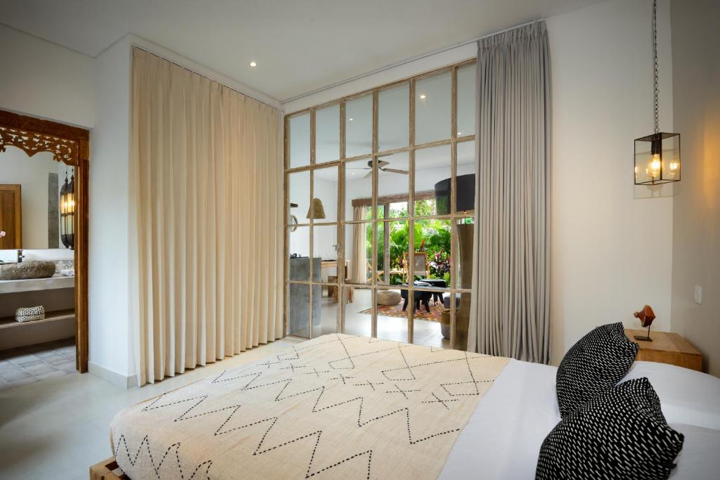 een slaapkamer met een bed en een groot raam bij TheSoulHouseBali in Canggu