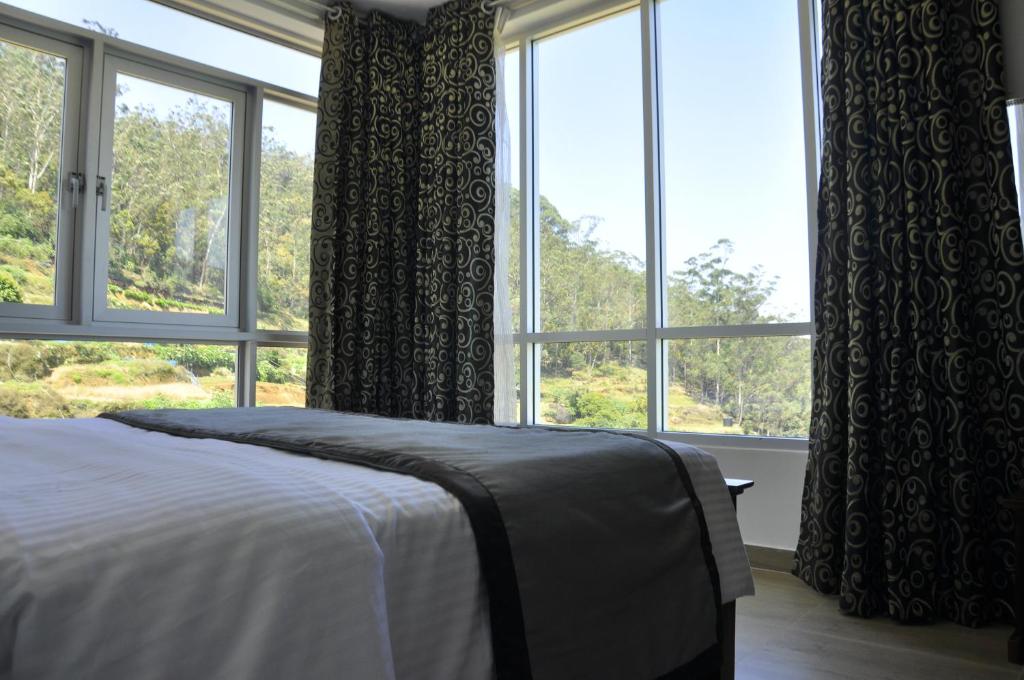a bedroom with a bed and a large window at Forest View Lodge in Nuwara Eliya