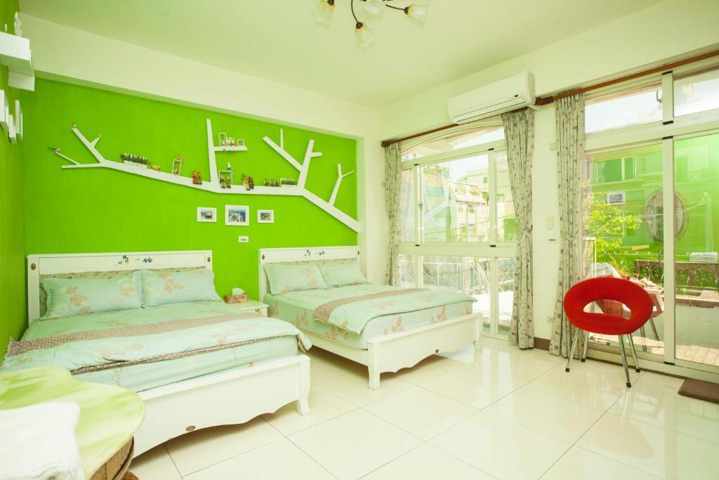 花蓮市にあるSunshine Guest Houseの緑のベッドルーム(ベッド2台、赤い椅子付)