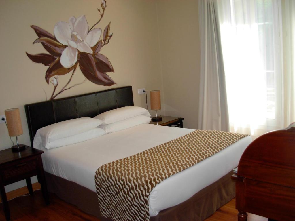 
a bed with a white bedspread and pillows at Hotel el Jardín de Eugenia in Ribadesella
