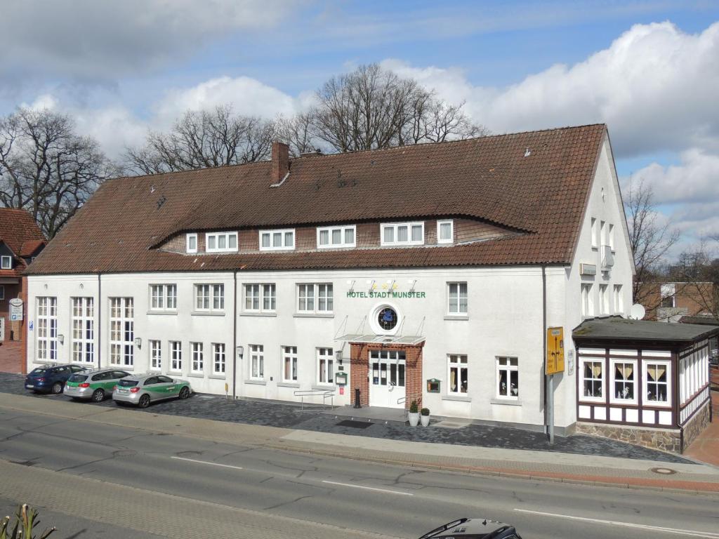 a large white building on the side of a street at Hotel Stadt Munster in Munster im Heidekreis