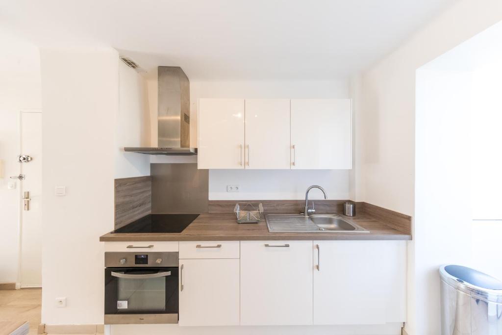 a kitchen with white cabinets and a sink at Résidence La Source in Toulon