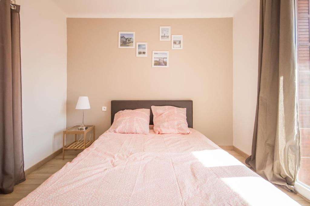 a bedroom with a bed with pink sheets and pillows at Résidence La Source in Toulon