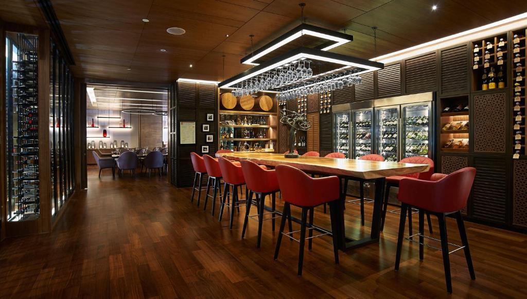 a dining room with a long table and red chairs at Amari Bangkok in Bangkok