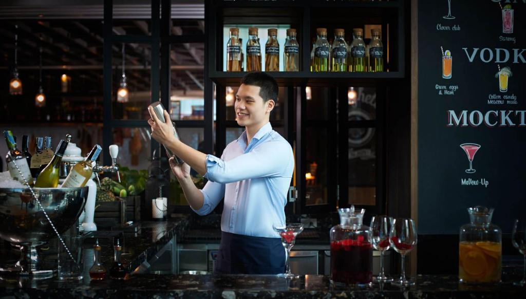 a bartender standing behind a bar with his hand up at Amari Bangkok in Bangkok