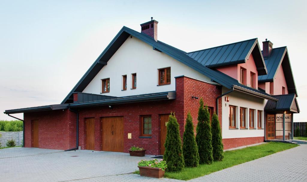 uma casa vermelha e branca com um telhado preto em Artis Dom Gościnny em Zamość