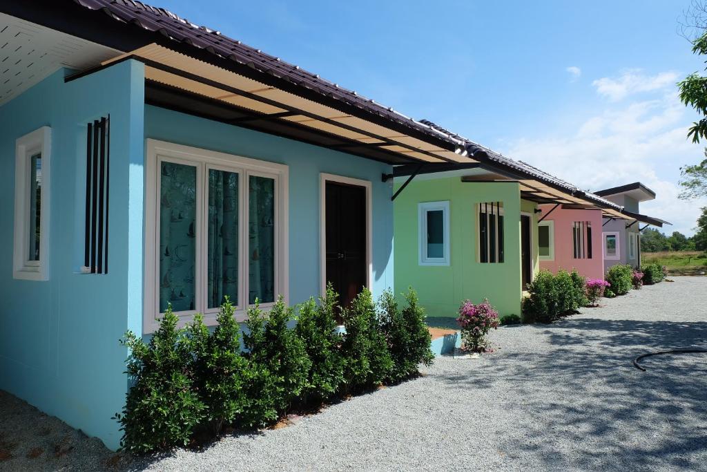 a row of colorful houses in a driveway at Maikhao Beach Guest House in Mai Khao Beach