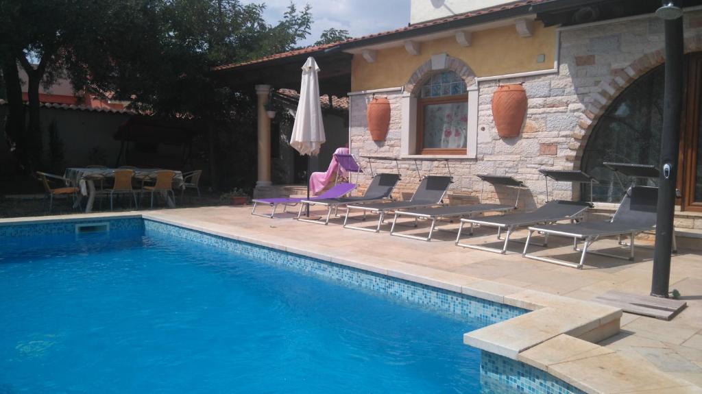 a pool with chairs and an umbrella next to a house at Rustic house with private Pool in Šišan