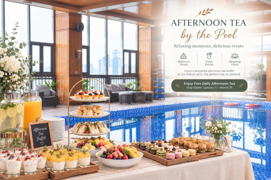 An indoor poolside afternoon-tea setup with pastries, fruit, and drinks.