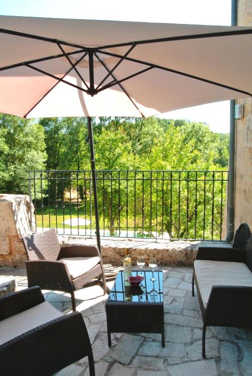 a patio with an umbrella and chairs and a table at Chambre d&#39;hôtes Au jardin de la Bachellerie in La Bachellerie
