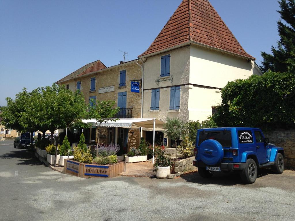 une jeep bleue garée devant un bâtiment dans l'établissement Logis Hôtel Restaurant La Bastide, à Villefranche-du-Périgord