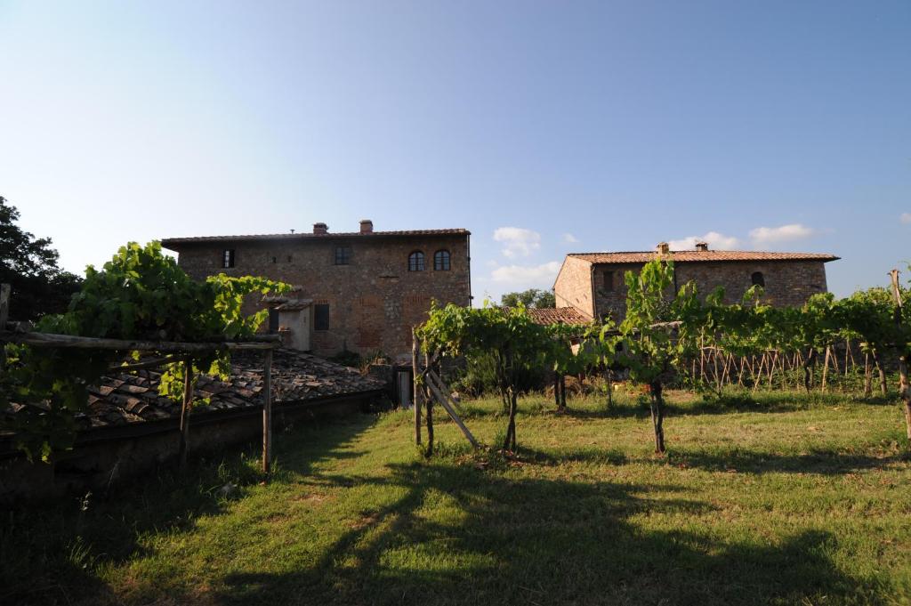 uma quinta com dois edifícios e árvores num campo em Agriturismo Scorgiano em Scorgiano