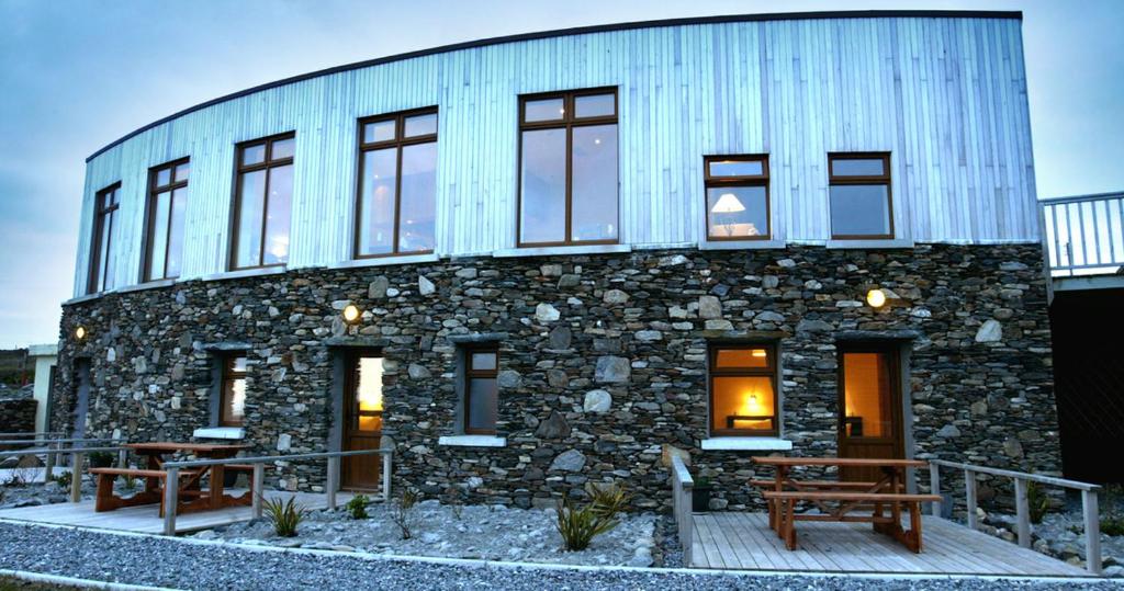 ein Steingebäude mit zwei Bänken davor in der Unterkunft Dolphin Hotel in Inishbofin