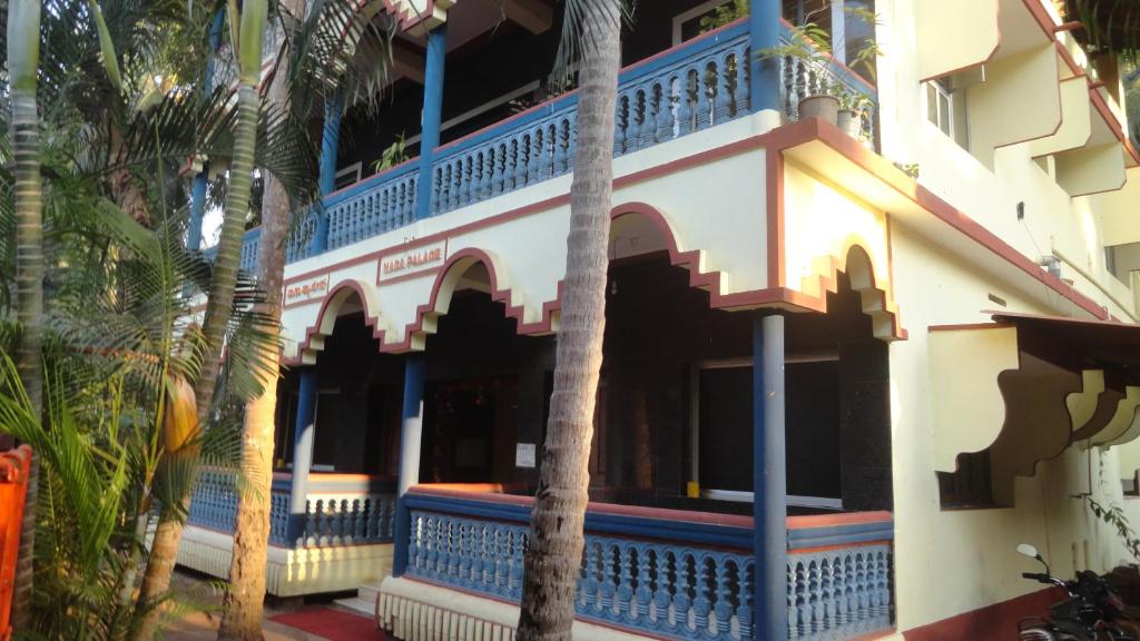 a building with blue trim and palm trees at Naga Palace in Gokarna