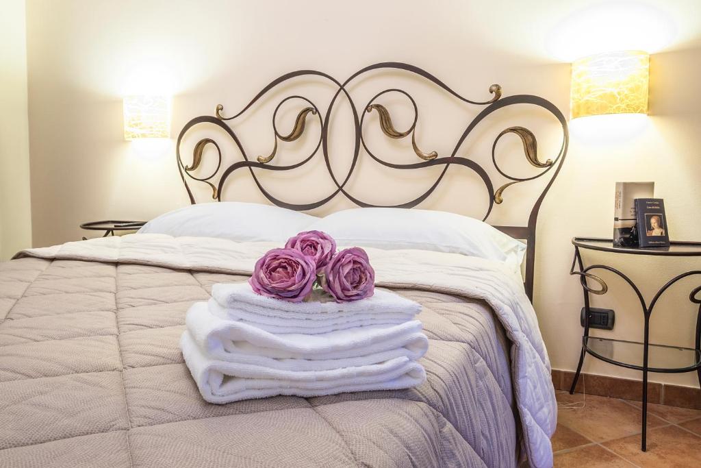 Una cama con toallas blancas y rosas púrpuras. en Costa Catterina B&B, en Castagnito