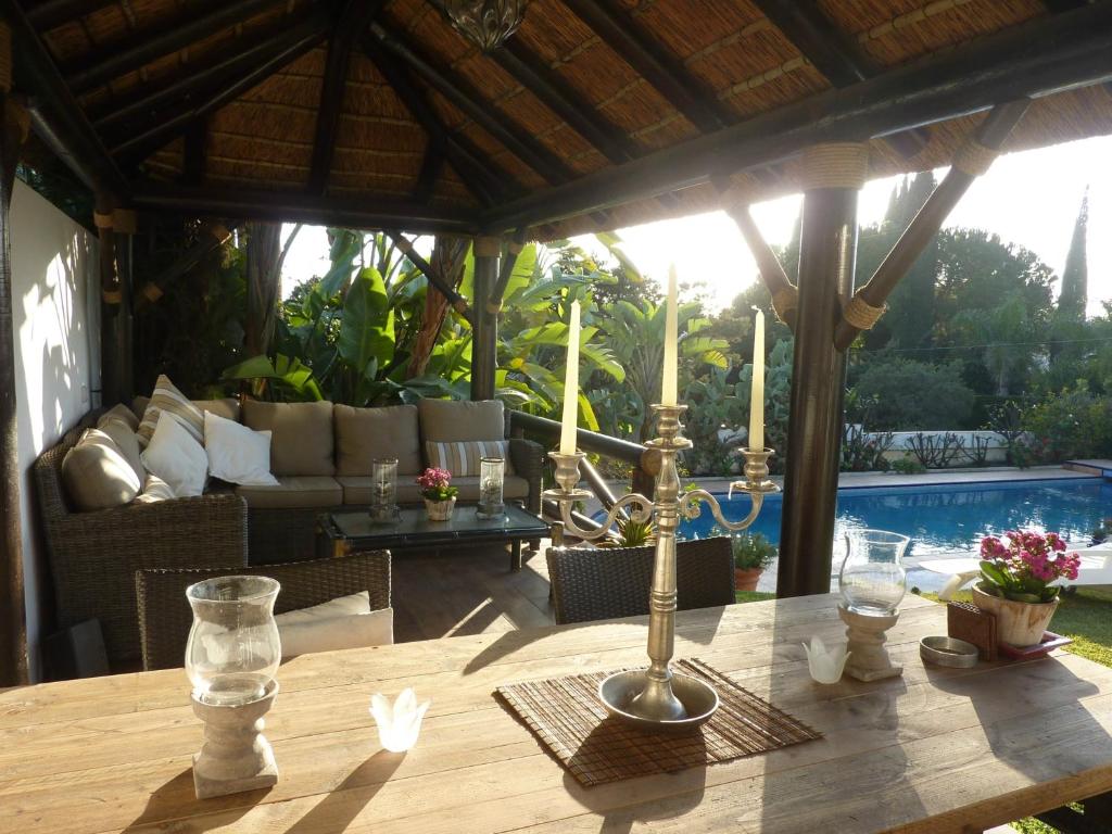 einen Holztisch in einem Pavillon mit einem Sofa und einem Tisch in der Unterkunft Villa Breeze Boutique Guest Rooms, Marbella in Marbella