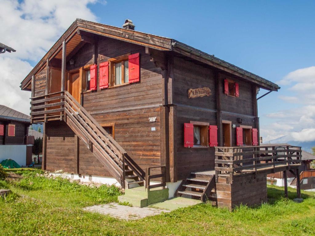een houten huis met rode ramen en een trap bij Chalet Alphütte in Rosswald