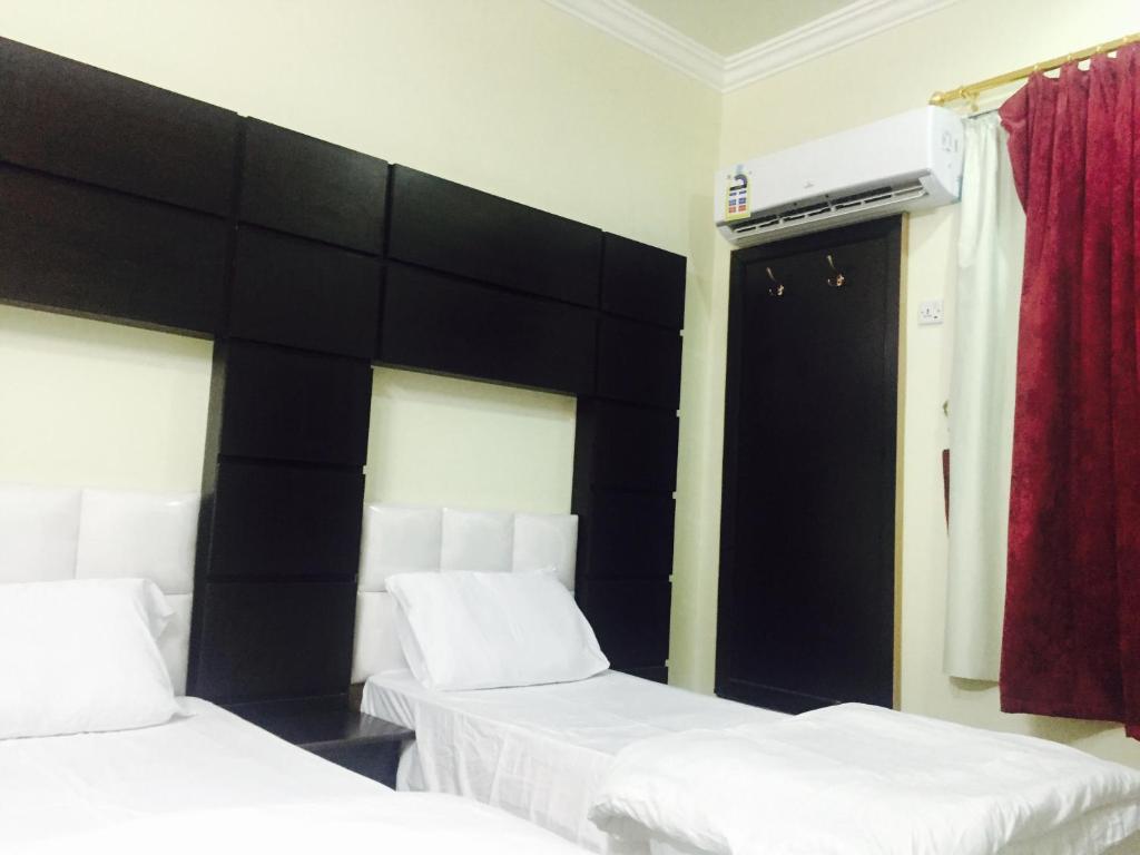 a bedroom with two beds and a black headboard at Qsr Al Balsem Aparthotel in Unayzah