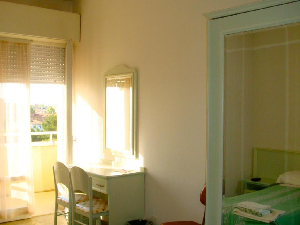 Zimmer mit einem Tisch, Stühlen und einem Fenster in der Unterkunft West End in Gatteo a Mare