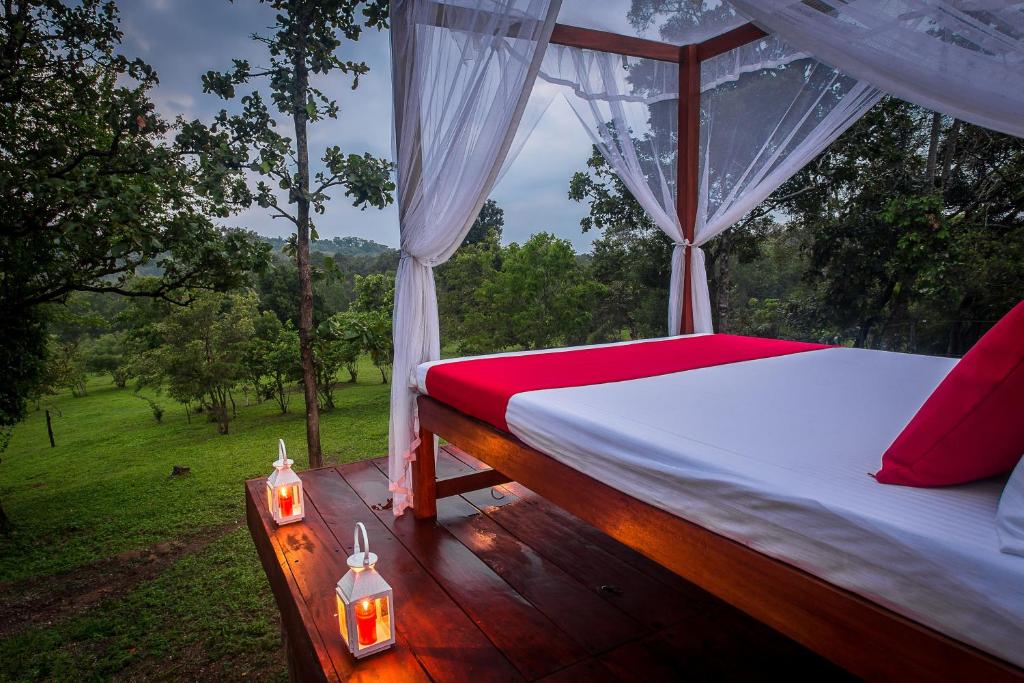 a bed on a deck with a view of a forest at Ahaspokuna by Eco Team in Belihul Oya