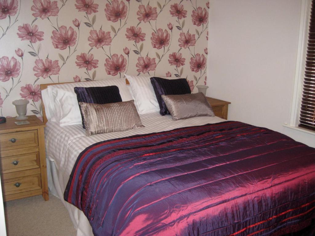 Taylors Guesthouse في ساليزبري: غرفة نوم مع سرير مع زهور على الحائط