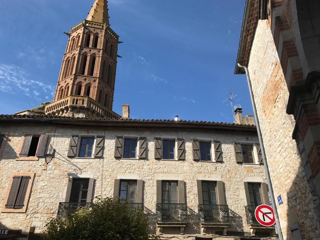 un edificio con una torre dell'orologio sopra di B&B Le Chat Qui Dort a Montricoux