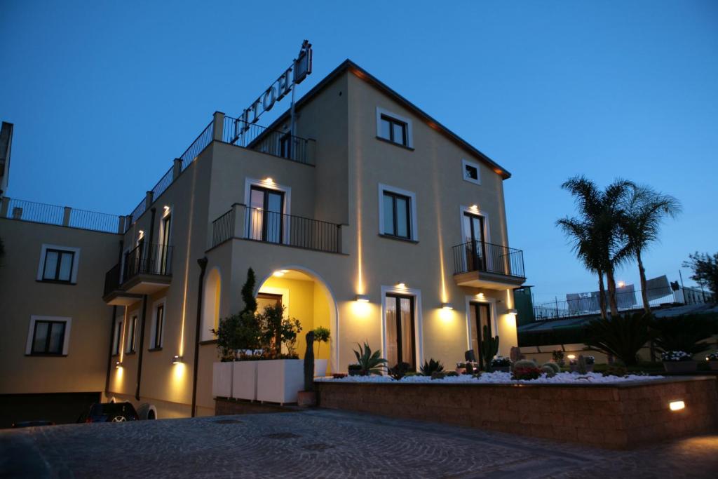 Un grand bâtiment blanc avec des lumières allumées la nuit dans l'établissement Hotel Visagi, à Pompéi