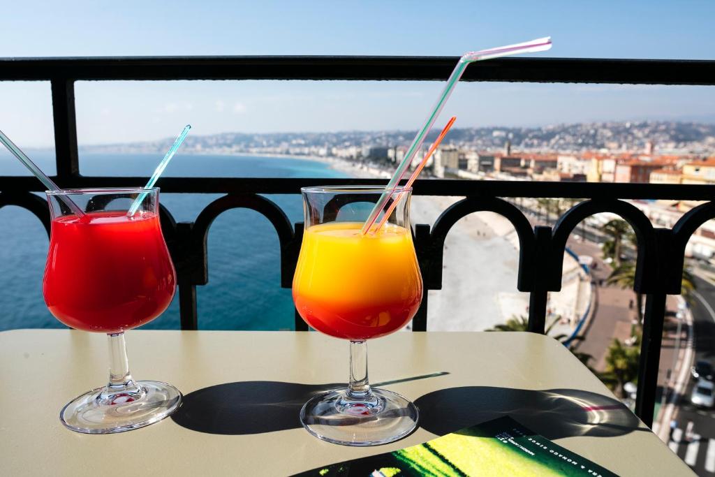two drinks sitting on a table on a balcony at Hotel Suisse in Nice