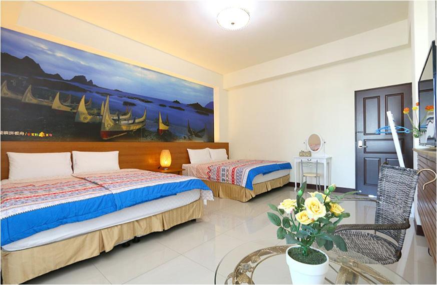 een slaapkamer met 2 bedden en een schilderij aan de muur bij Sweet Home in Taitung in Taitung