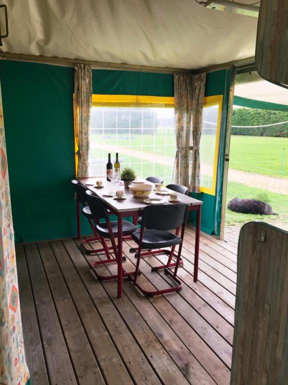 einen Tisch und Stühle auf einer Veranda mit einem Tisch und einem Fenster in der Unterkunft Recreational Farm Camping de Kreitsberg in Zeeland