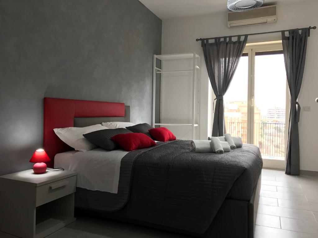 a bedroom with a bed with red pillows and a window at Dunant House in Rome