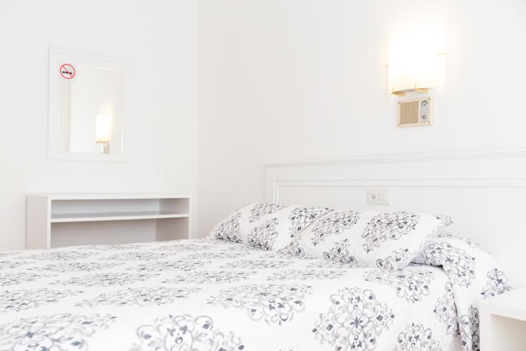 a white bedroom with a bed with white sheets at Rey Fernando in Santiago de Compostela