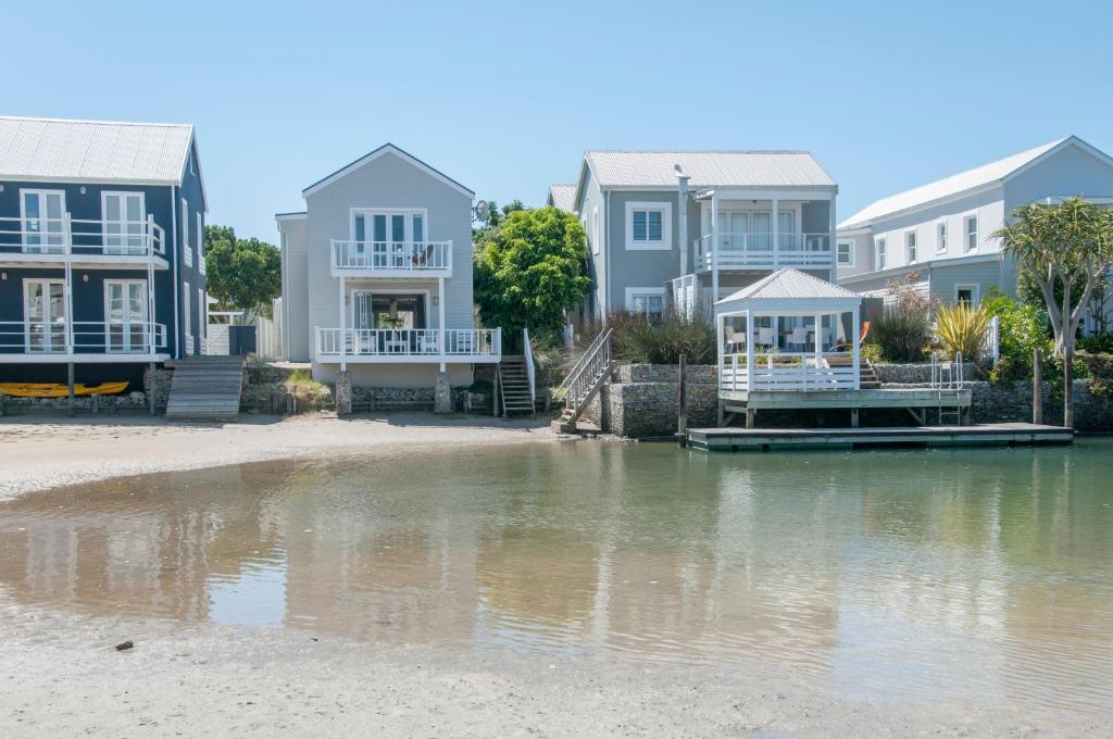 a row of houses on a beach next to a body of water at Avocet Cottage in Knysna