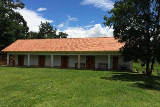 um edifício com um telhado vermelho e um jardim de relva em Recanto da Maya em Santo Antônio do Pinhal