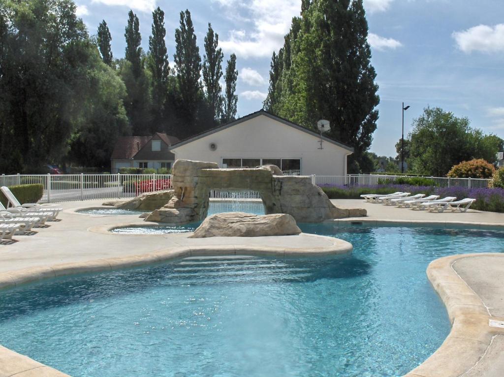 a swimming pool with a waterfall in a yard at Camping Du Port De Plaisance in Péronne