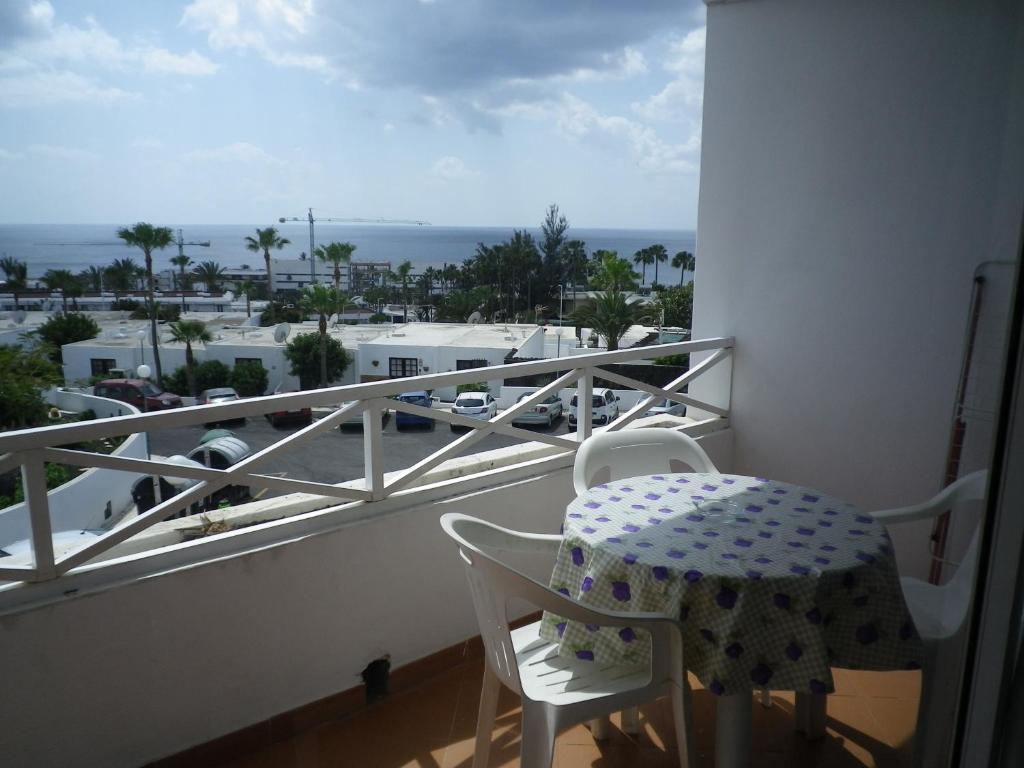 a balcony with a table and chairs and a view of the ocean at Viviendas Las Vistas in Puerto del Carmen