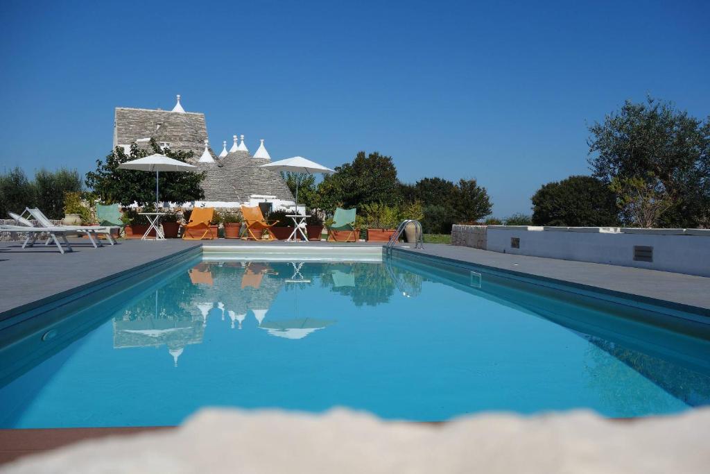 - une piscine d'eau bleue en face d'une maison dans l'établissement Masseria Serralta, à Locorotondo