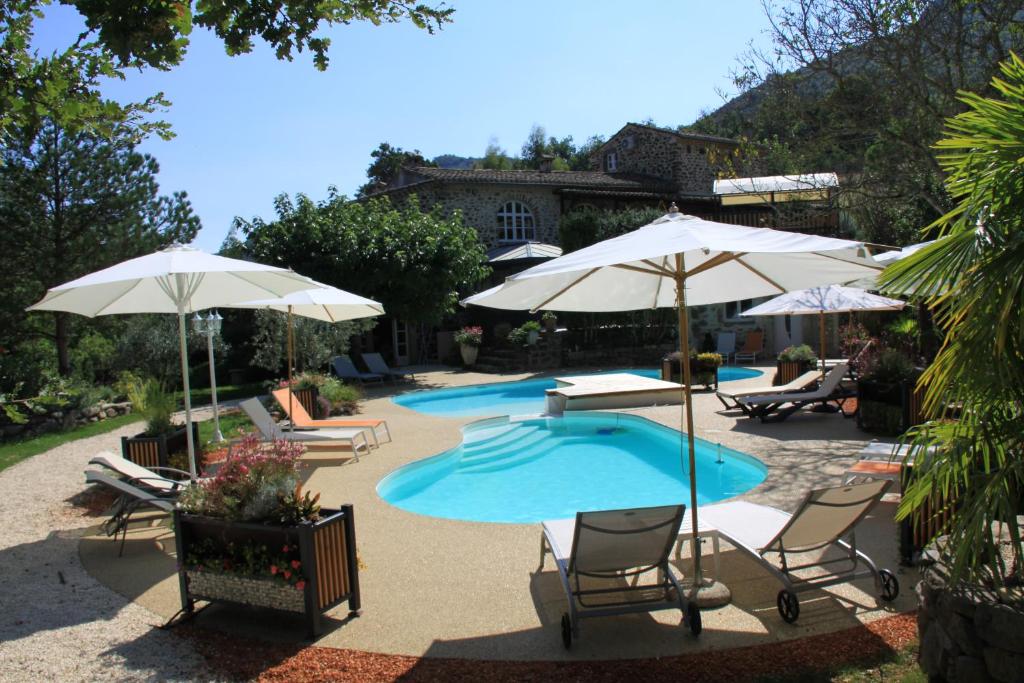 a patio with chairs and umbrellas and two swimming pools at Ferme du Pic d'Allier in Saint-Martin-le-Supérieur