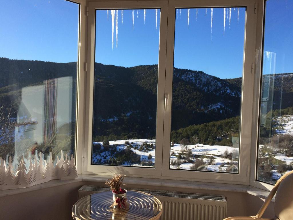 Zimmer mit einem Tisch vor den Fenstern mit Eiszapfen in der Unterkunft Anarada Guesthouse in Synikia Mesi Trikalon