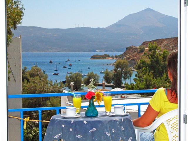 een vrouw aan een tafel met uitzicht op het water bij Hotel Delfini in Adamas