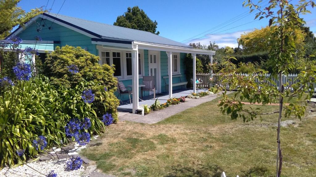 une maison bleue avec des fleurs dans la cour dans l'établissement Ferntree Cottage, à Mapua