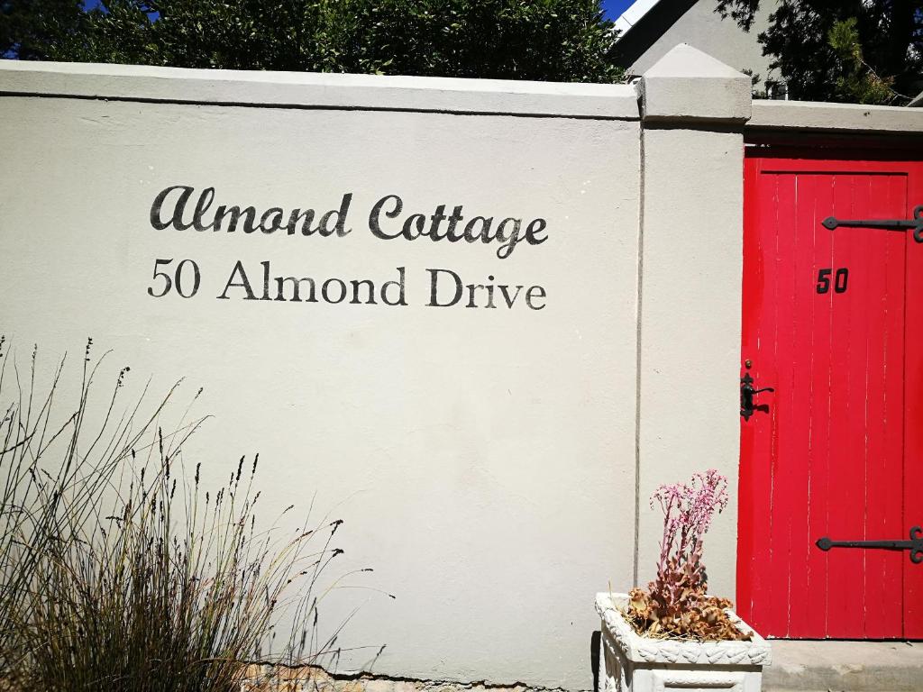 een bord voor een amandelhuisje en een rode deur bij Almond Cottage Bed & Breakfast in Somerset West