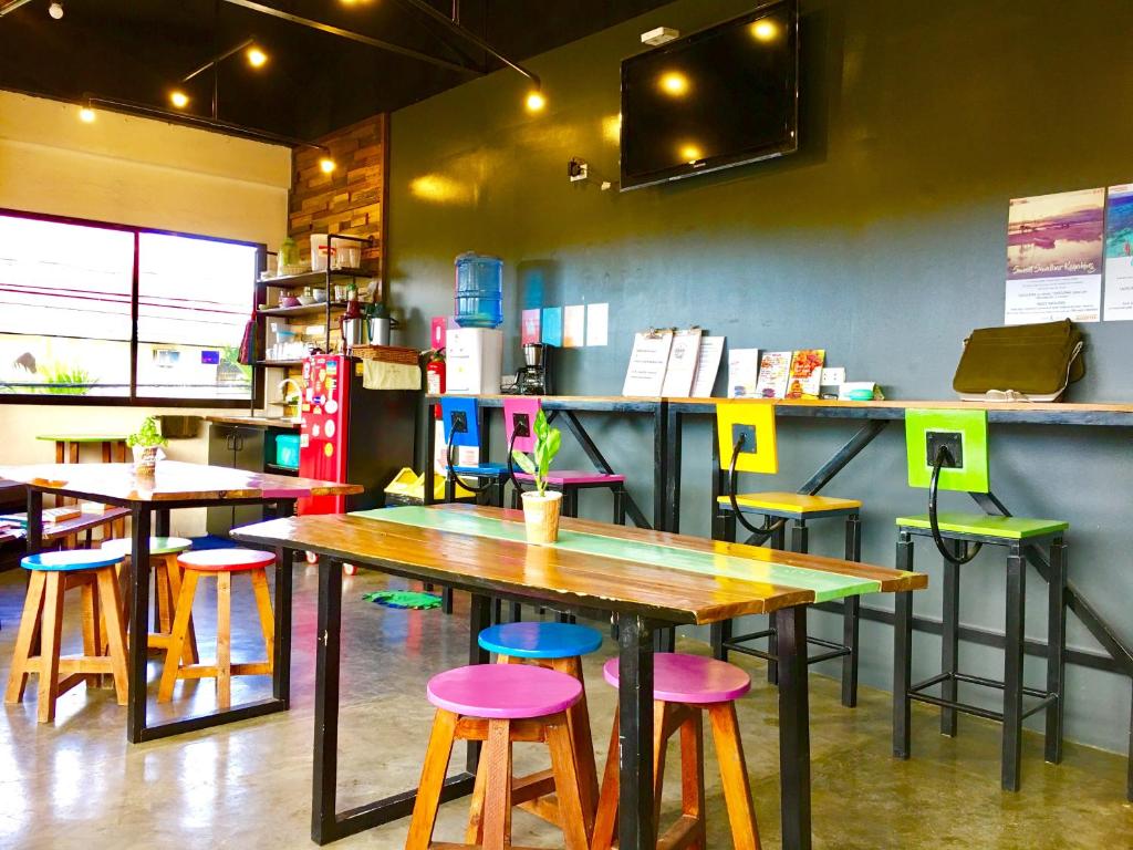 a restaurant with tables and stools in front of a counter at Moon Fools Hostel in Panglao