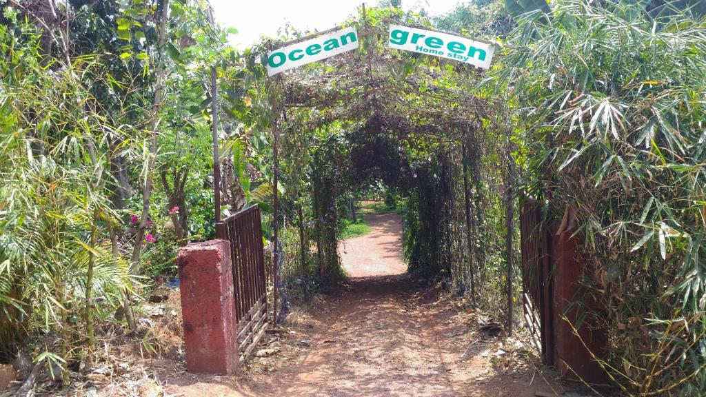 an entrance to a garden with an arch with a street sign at Ocean Green Kerala in Kannur