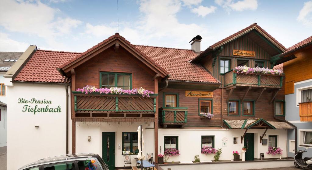 a building with flowers on the balconies of it at Das kleine Bio Hotel Tiefenbach in Schladming