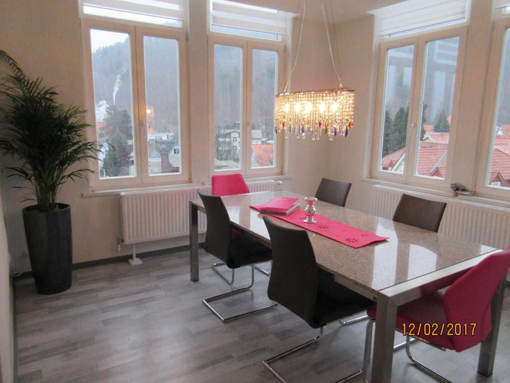 een eetkamer met een tafel, stoelen en ramen bij FeWo Witt Annenburg in Bad Harzburg