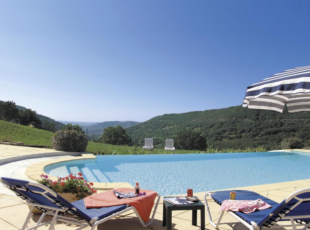 uma piscina com duas cadeiras e uma mesa em Logis Hôtel-restaurant La Mère Biquette em Saint-Pons