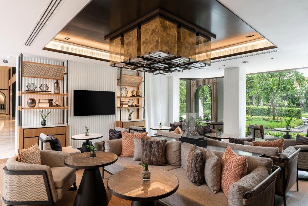 A garden-facing lobby lounge with a wall-mounted television and layered seating.