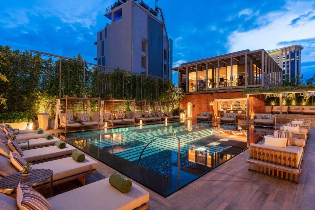 A warmly lit evening pool courtyard framed by loungers and cabanas.